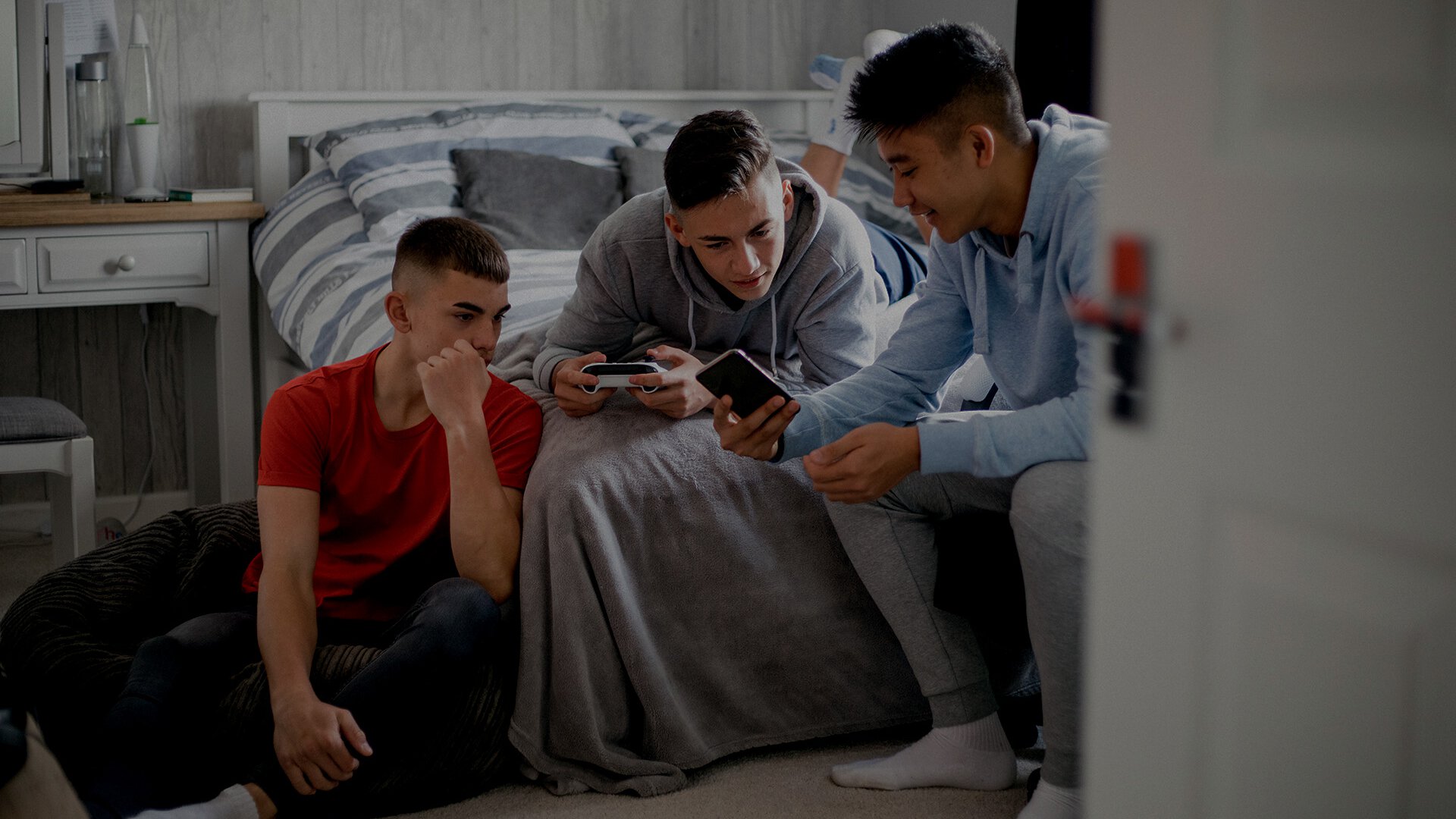 Drei männliche Teenager haben ein Handy in der Hand und zeigen sich was